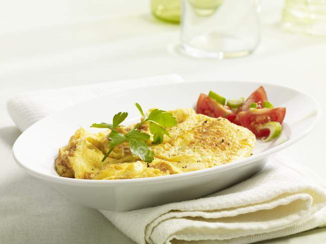 Scrambled egg with a tomato salad on white plate over towel — Stock Photo
