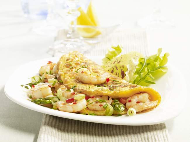An omelette with king prawns and asparagus on white plate  over towel — Stock Photo