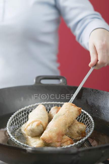 Woman frying spring rolls in wok — Stock Photo