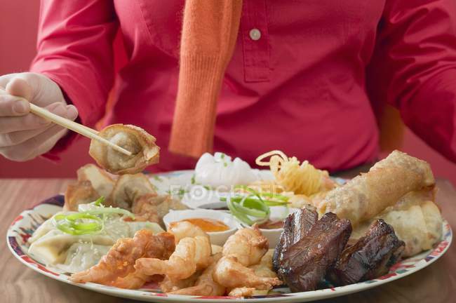 Крупный план женщины с палочками для еды и азиатскими закусками — стоковое фото