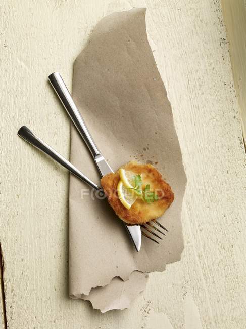 Escalope with lemon on cutlery — Stock Photo