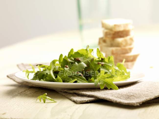 Vue rapprochée de la salade fusée et des tranches de pain blanc — Photo de stock