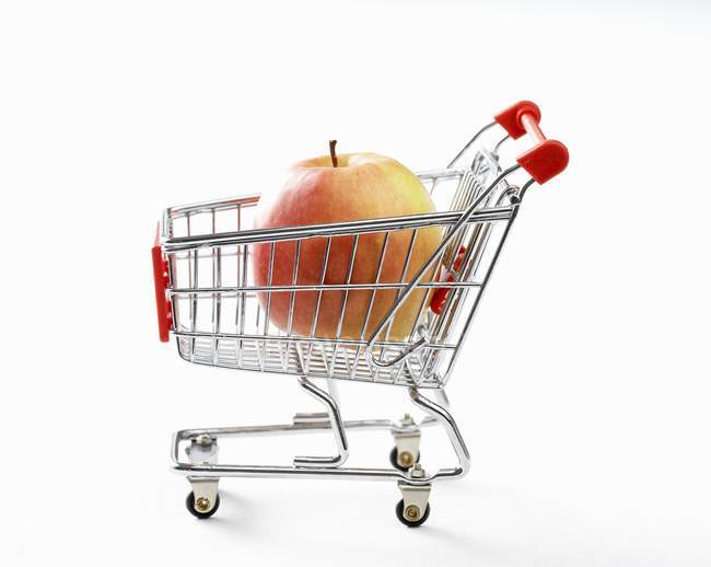 Manzana fresca en carro de compras de juguete - foto de stock