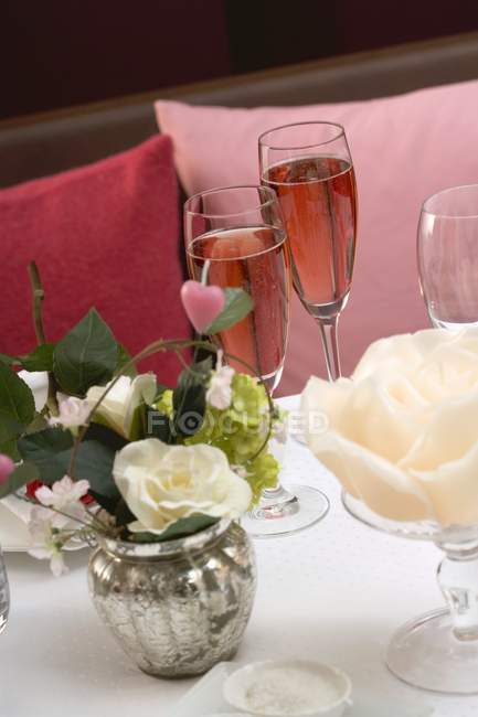 Copas de champán rosa en la mesa romántica - foto de stock