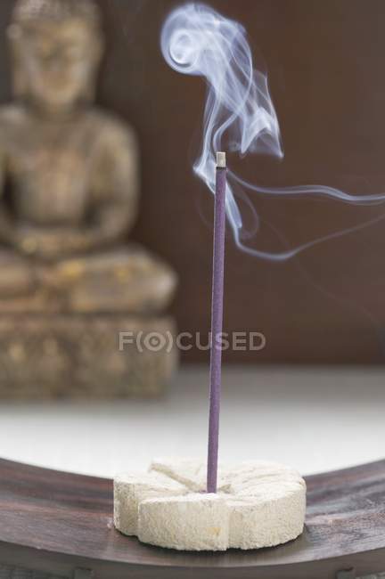 Vista de cerca de fumar palo de incienso delante de la estatua de Buda - foto de stock