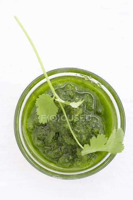 Primer plano vista superior de la salsa Mojo verde en vidrio con hierba - foto de stock