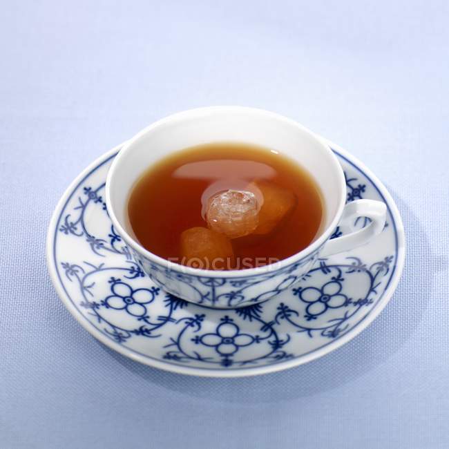 Té con cristales de azúcar en taza y platillo - foto de stock