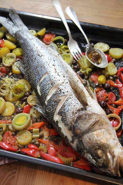 Baked sea bass on bed of vegetables — Stock Photo