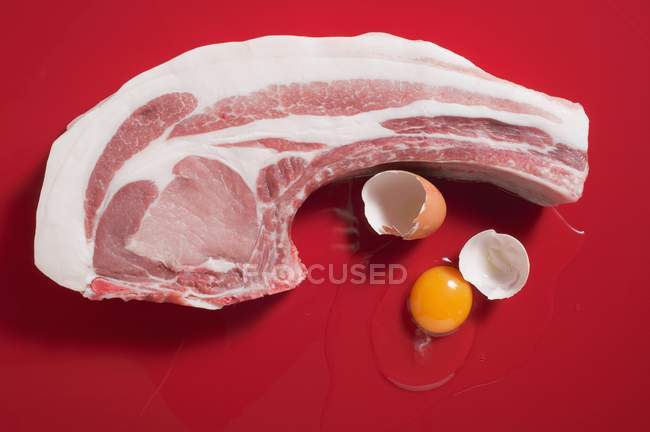 Organic pork chop and broken egg — Stock Photo