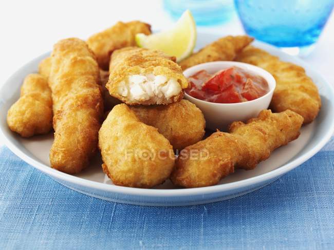 Closeup view of haddock Goujons with lime wedge and sauce — Stock Photo