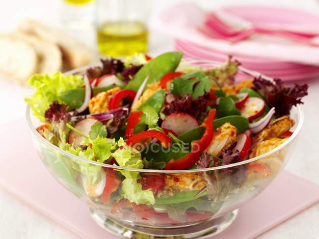 Thailändischer Hühnchensalat in Glasschale über rosa Schreibtisch auf weißer Oberfläche — Stockfoto