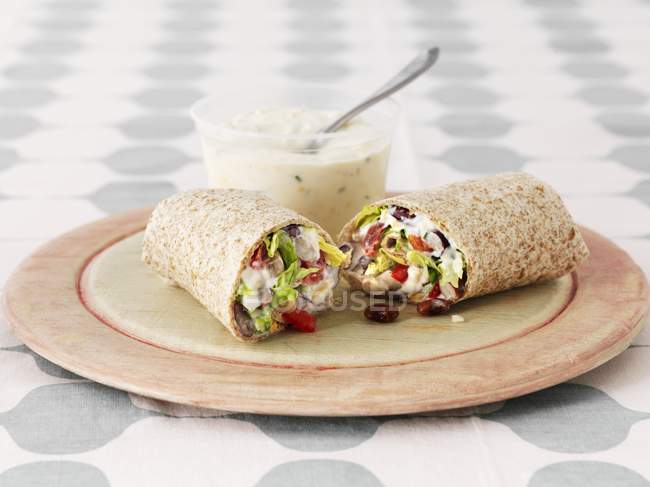 Closeup view of wholemeal wraps with salad and sauce on plate — Stock Photo