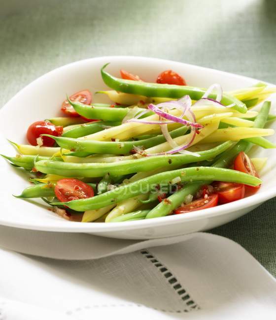 Salade de haricots avec tomates et oignons sur une assiette blanche sur une serviette — Photo de stock