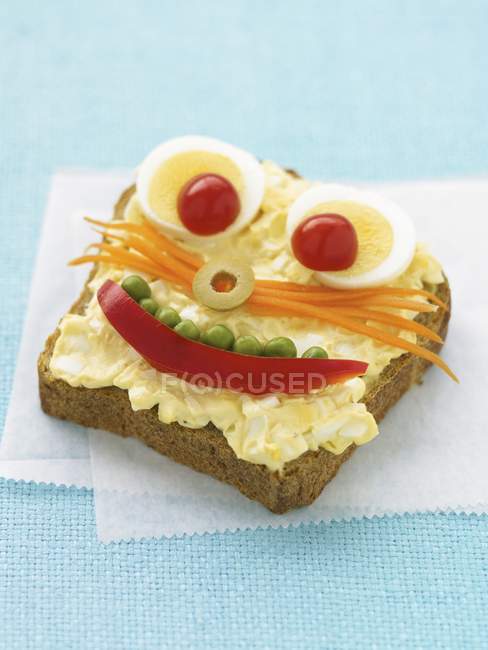 Uma fatia de pão com um rosto engraçado sobre guardanapo de papel — Fotografia de Stock
