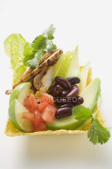 Vista de cerca de pollo con verduras, lima y hojas de cilantro en cáscara de maíz - foto de stock