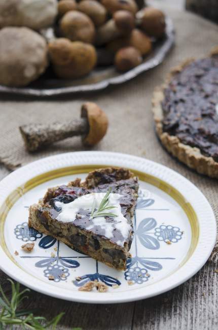 Elevated view of a mushroom tart slice and raw mushrooms on background — Stock Photo