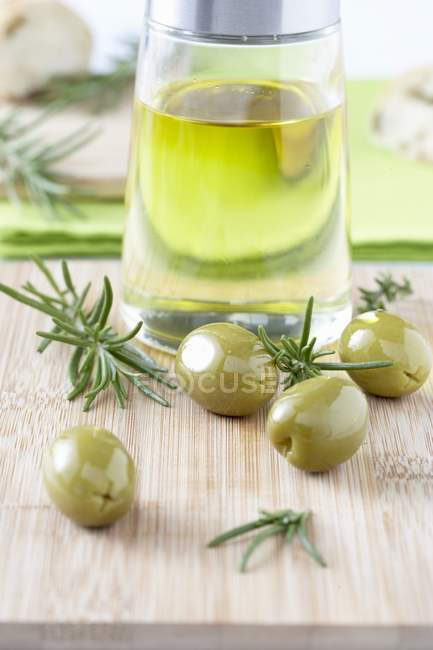 Olivenöl mit grünen Oliven und Rosmarin — Stockfoto
