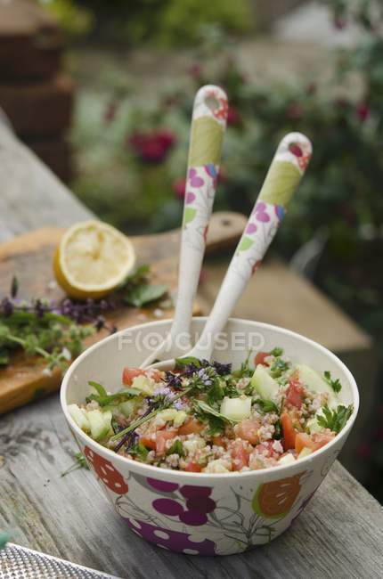 Tabbouleh with tomatoes, cucumber and chives in bowl wth spoons — Stock Photo