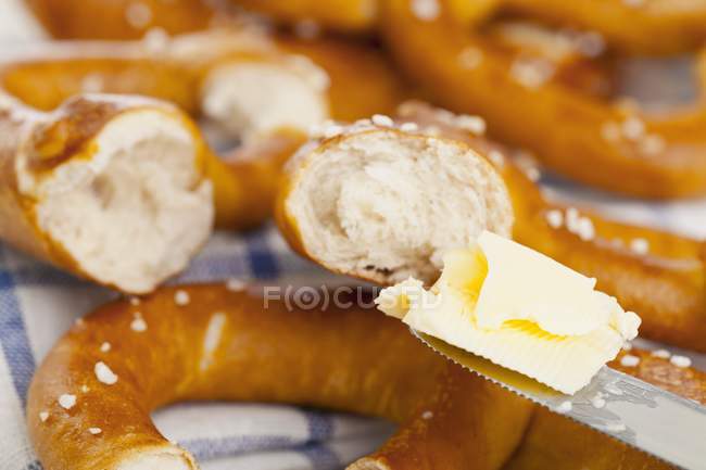 Pretzels sendo espalhados com manteiga — Fotografia de Stock