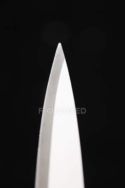 Vista de cerca del punto de una hoja de cuchillo sobre fondo negro - foto de stock