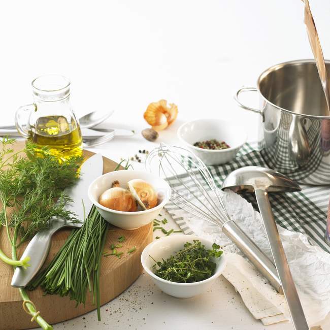 Stillleben mit Kräutern, Öl, Zwiebeln und Gewürzen auf Tisch und weißem Hintergrund — Stockfoto