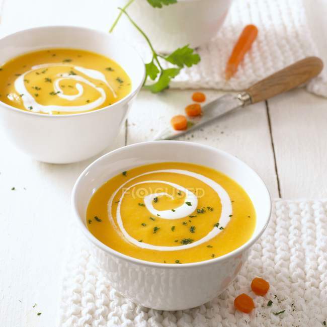 Bowls of carrot soup with swirls of cream — Stock Photo