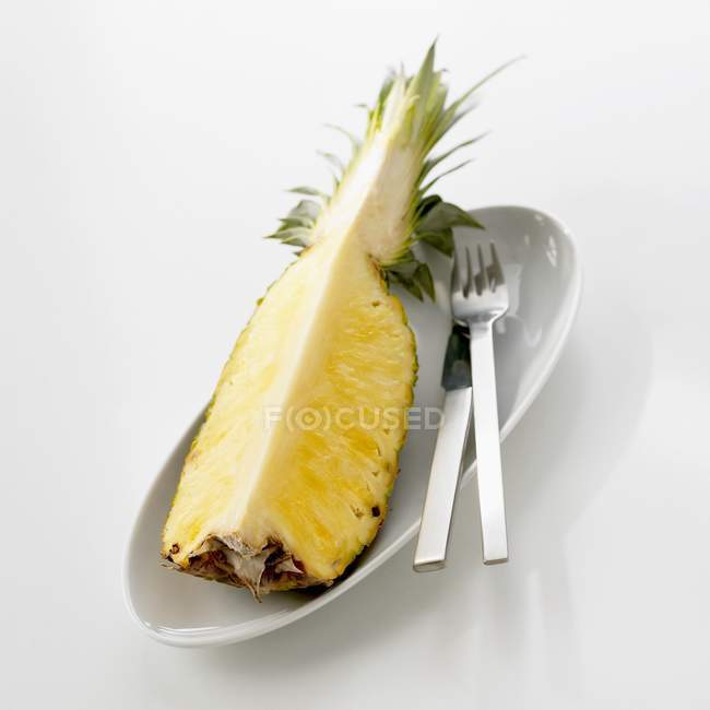 Pineapple quarter in dish with knife — Stock Photo