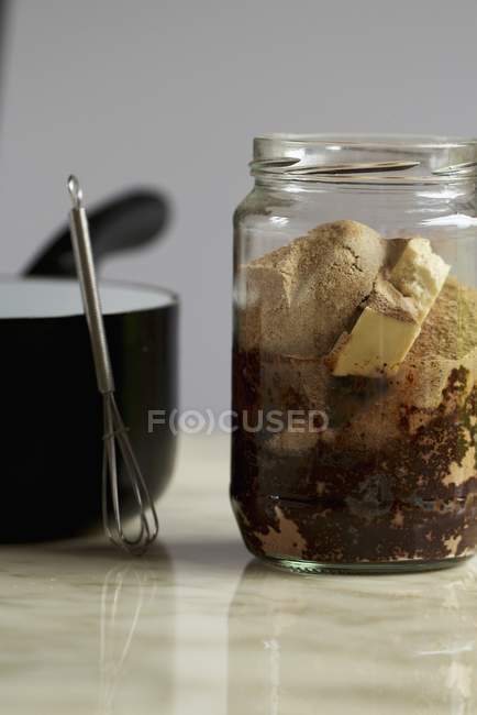Vue rapprochée des ingrédients pour le chocolat végétalien dans un pot en verre — Photo de stock