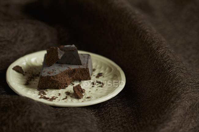 Vista de cerca de trozos de barra de chocolate en el plato - foto de stock