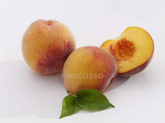 Спелые персики с листьями — стоковое фото