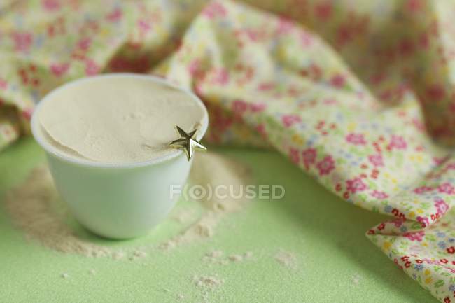 Closeup view of baobab powder in small cup with star and floral patterned cloth — Stock Photo