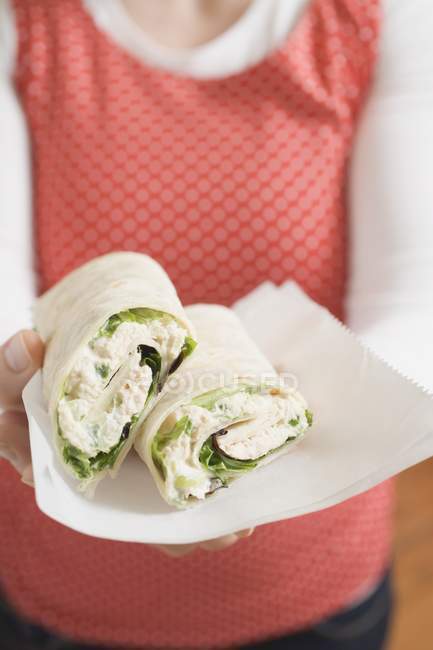 Closeup view of woman holding two tuna wraps on paper — Stock Photo