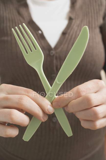 Обрезанный вид женщины с пластиковым ножом и вилкой — стоковое фото