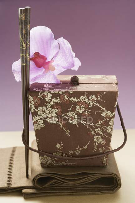 Vue rapprochée du conteneur asiatique avec orchidée et baguettes — Photo de stock