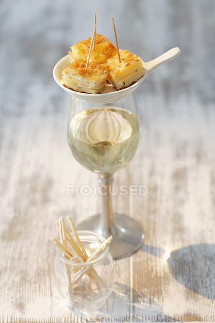 Potato tortilla on small plate over glass over wooden surface — Stock Photo