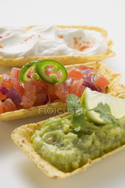 Guacamole, salsa de tomates et crème sure en coquilles de tacos sur fond blanc — Photo de stock