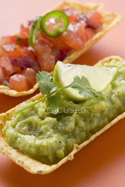 Guacamole and tomato salsa in taco shells over pink surface — Stock Photo