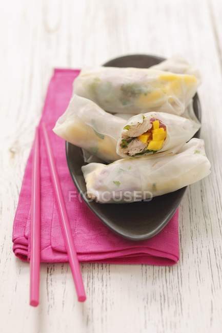 Involtini primavera con tacchino, mango, cipolle rosse ed erbe aromatiche sul piatto sopra un asciugamano rosa — Foto stock