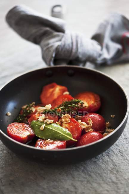 Fried tomatoes with herbs and oats on black plate — Stock Photo