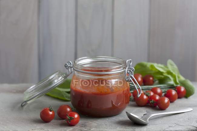 Tomato sugo in jar  over wooden surface and background — Stock Photo