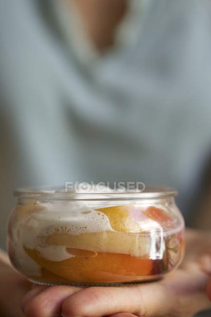Closeup cropped view of person holding poached peaches with roses, vanilla and cream — Stock Photo