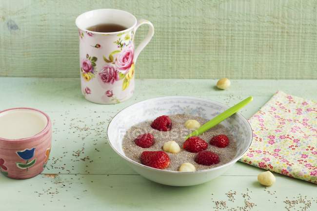 Closeup view of porridge with chia seeds, macadamia nuts and fresh strawberries — Stock Photo