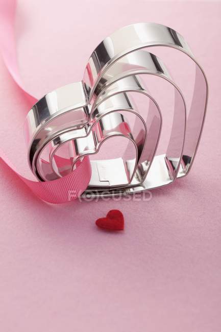 Closeup view of heart-shaped cookie cutters in various sizes and red heart — Stock Photo