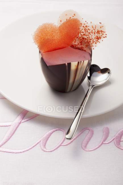 Closeup view of pink praline decorated with hearts on a cloth embroidered with the word Love — Stock Photo
