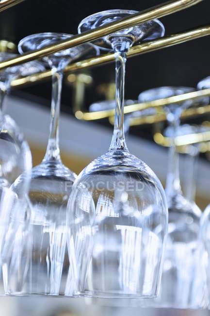 Vista close-up de copos de vinho de cabeça para baixo em um rack em um restaurante — Fotografia de Stock