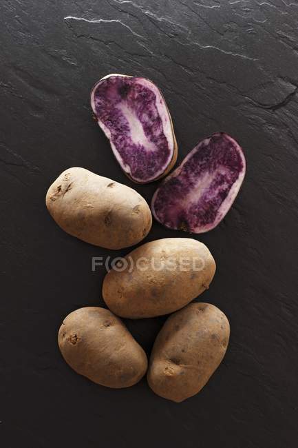 Whole and halved Blauer Schwede potatoes — Stock Photo
