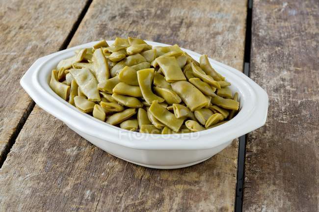 Cooked green beans in a dish on wooden surface — Stock Photo