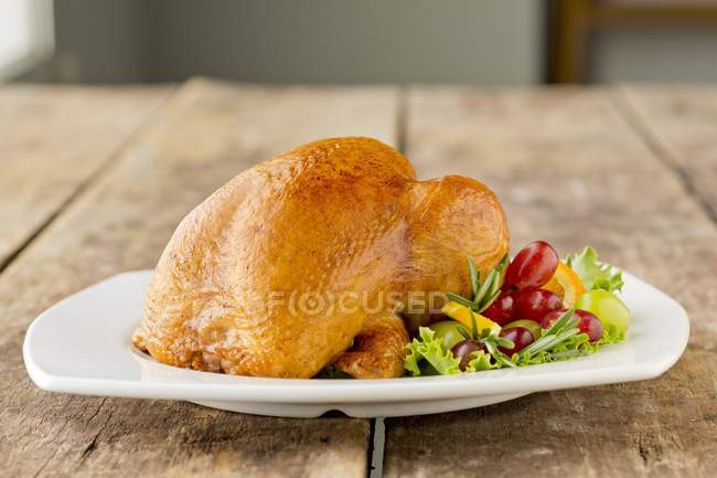 Целый жареный цыпленок на белой тарелке — стоковое фото