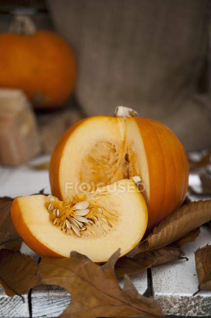 Sliced pumpkin with autumnal leaves — Stock Photo