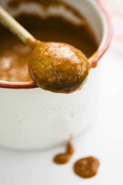 Closeup view of homemade peach sauce dripping from wooden spoon — Stock Photo